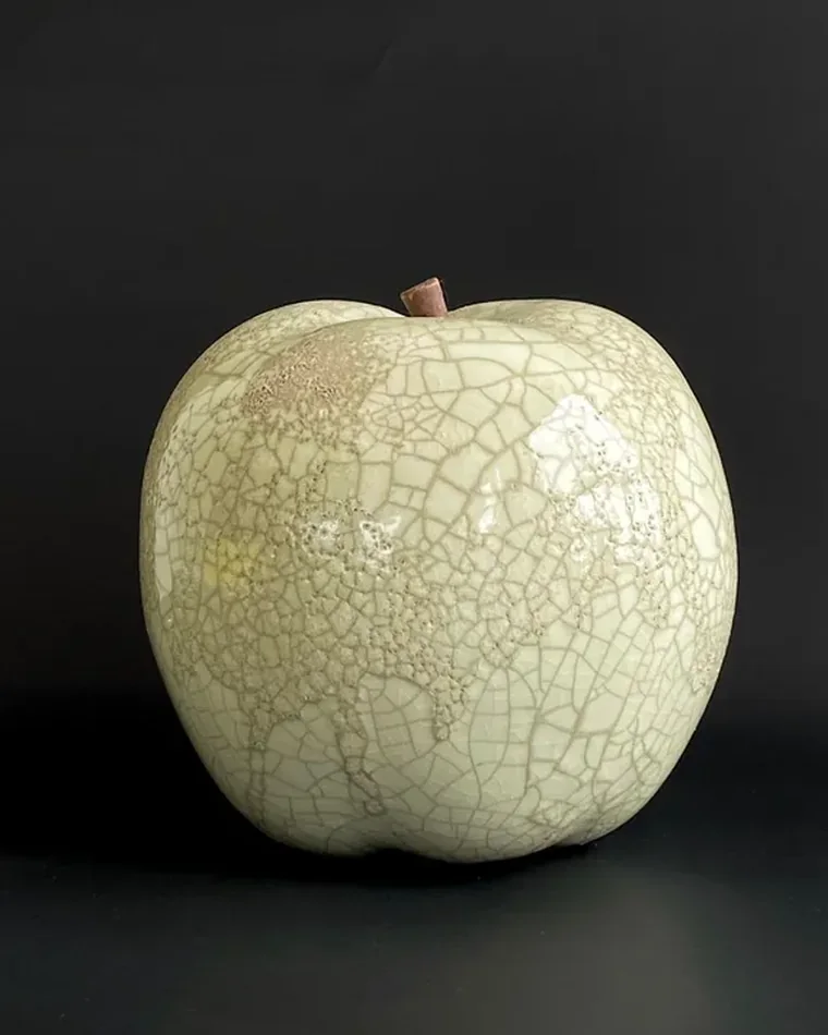 Dettaglio di uno smalto ceramico chiaro percorso da un fitto reticolo di screpolature su fondo scuro