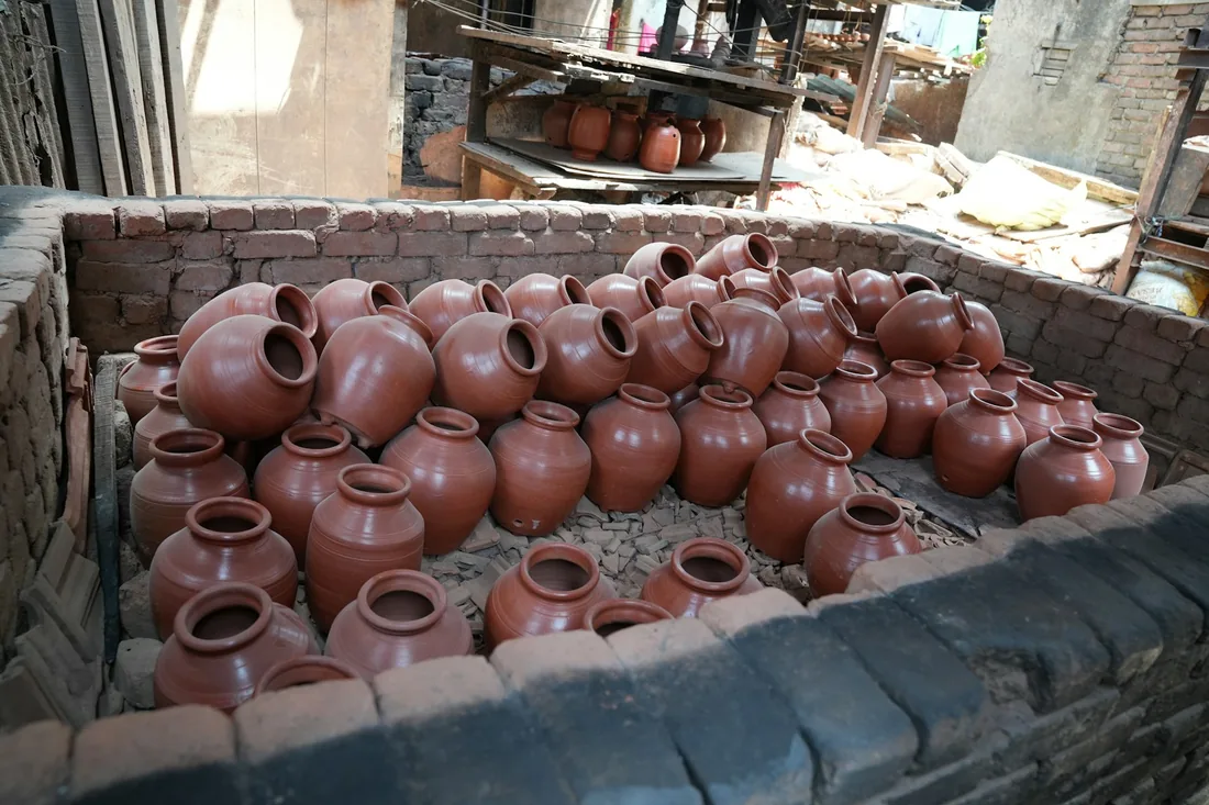 Recipienti in terracotta disposti fitti all'interno di una fornace in mattoni prima della cottura